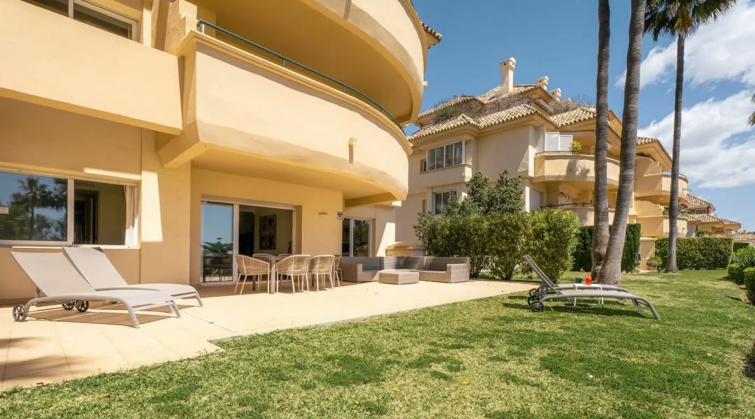 Garden terrace photographed by Troyan with lawn, palms and blue sky
