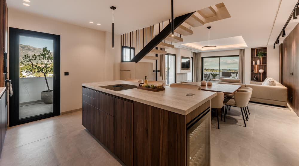 Kitchen island in stone and walnut with a staircase behind