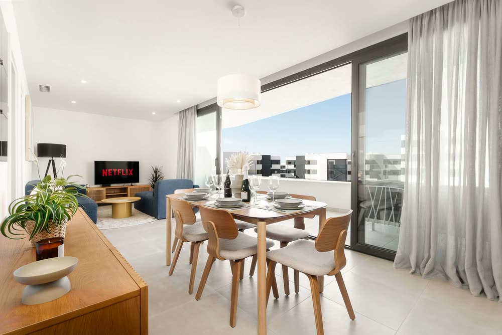 Dining table by floor-to-ceiling windows in a bright apartment