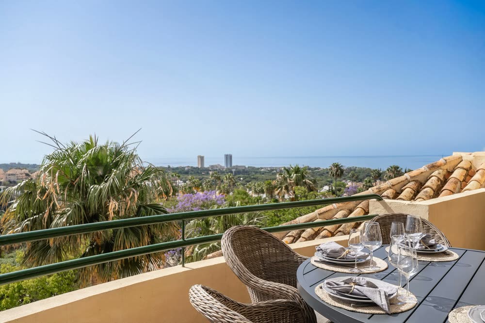Balcony set for lunch overlooking palm trees and the coast