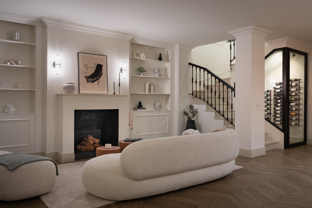 Sitting room with a curved sofa, fireplace and staircase