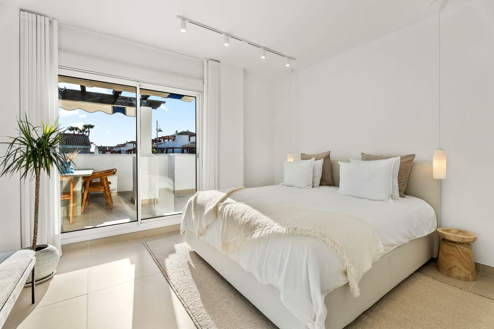 White bedroom opening onto a sunny terrace