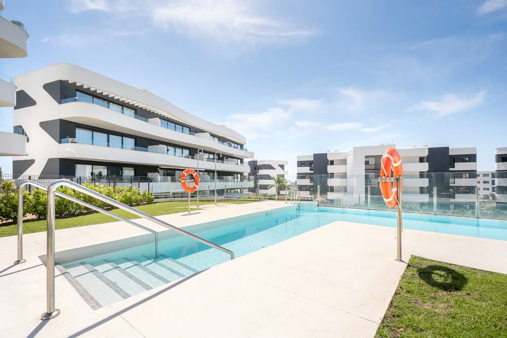 Communal pool with steps, lawn and modern apartment blocks